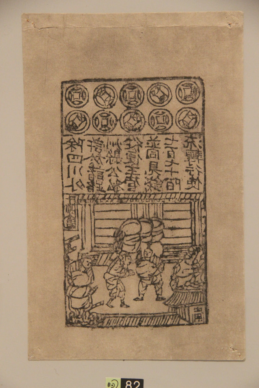 A museum display of Northern Song paper currency showing coin motifs, Chinese text and a market scene.
