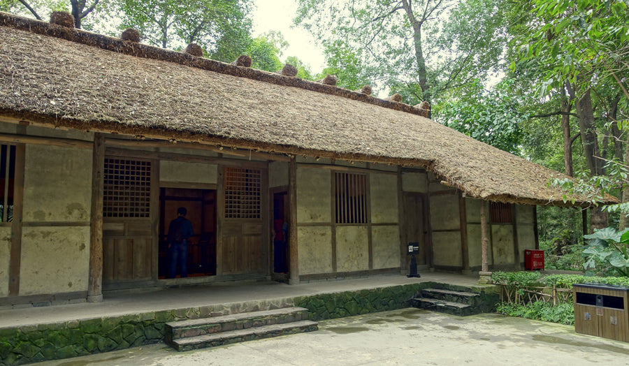 Du Fu's thatched cottage in Chengdu, with two visitors seen from behind at the doorway.