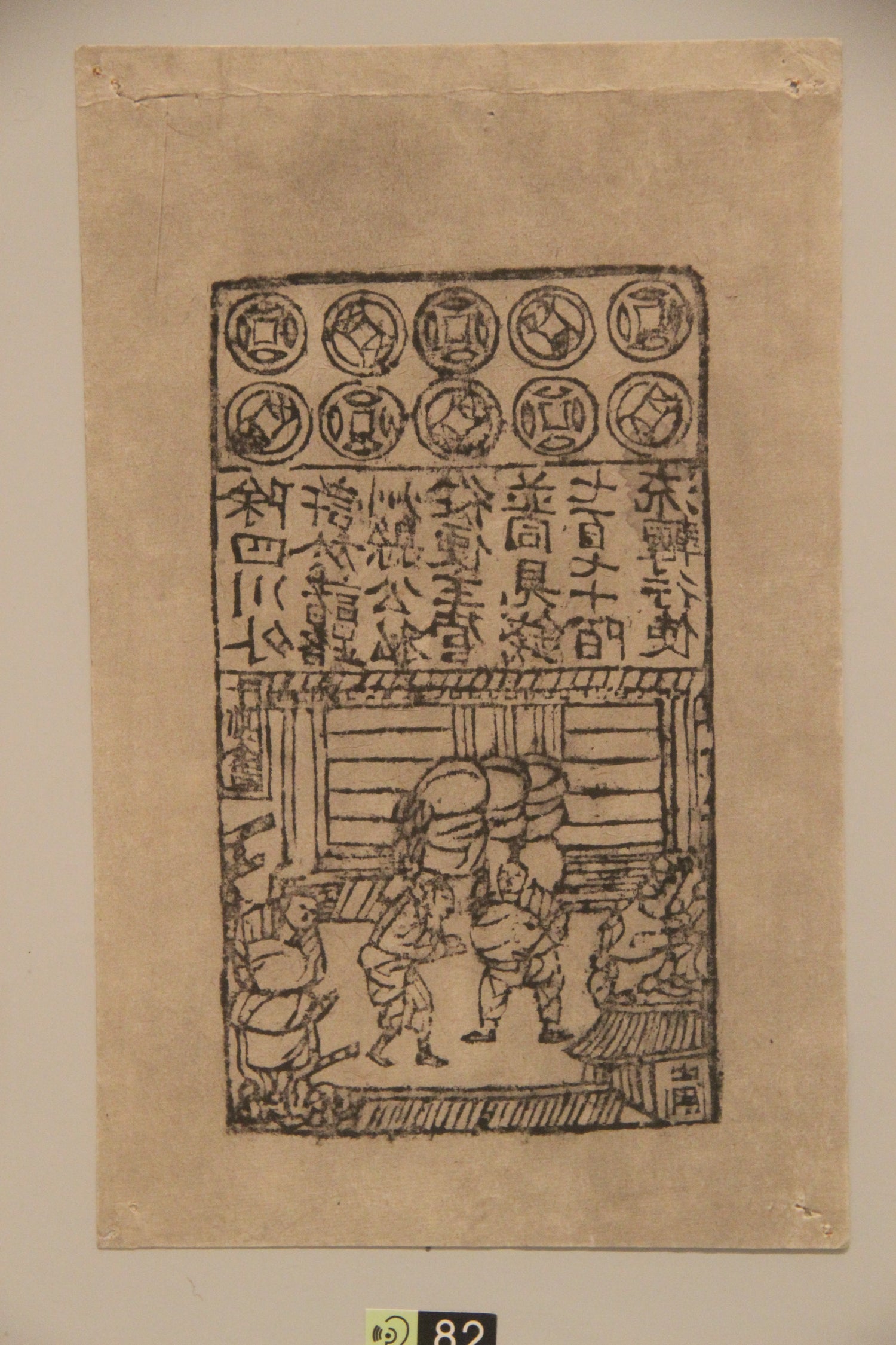 A museum display of Northern Song paper currency showing coin motifs, Chinese text and a market scene.