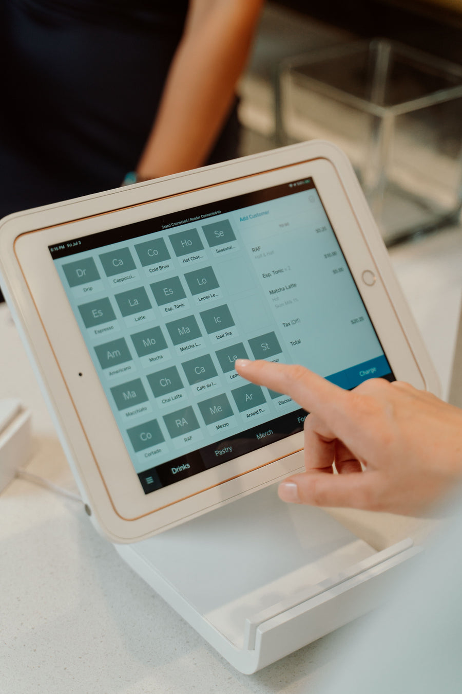 A hand selecting items on a touchscreen order terminal in a retail setting.