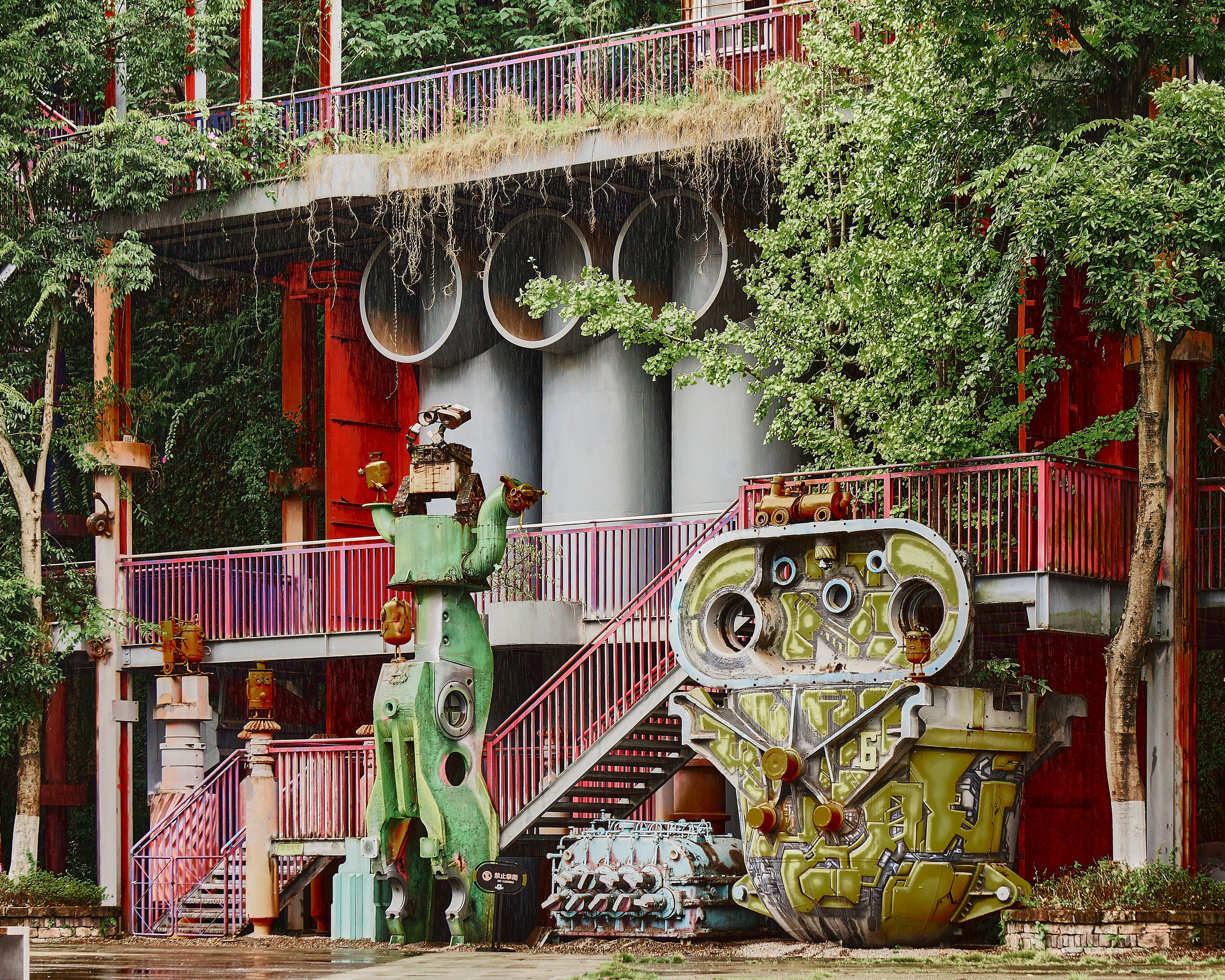 Machinery-based art installations among trees at a former steel plant in Chongqing.
