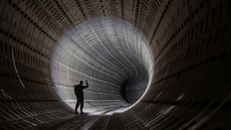 Silhouetted visitor standing inside a vast curved industrial tunnel.