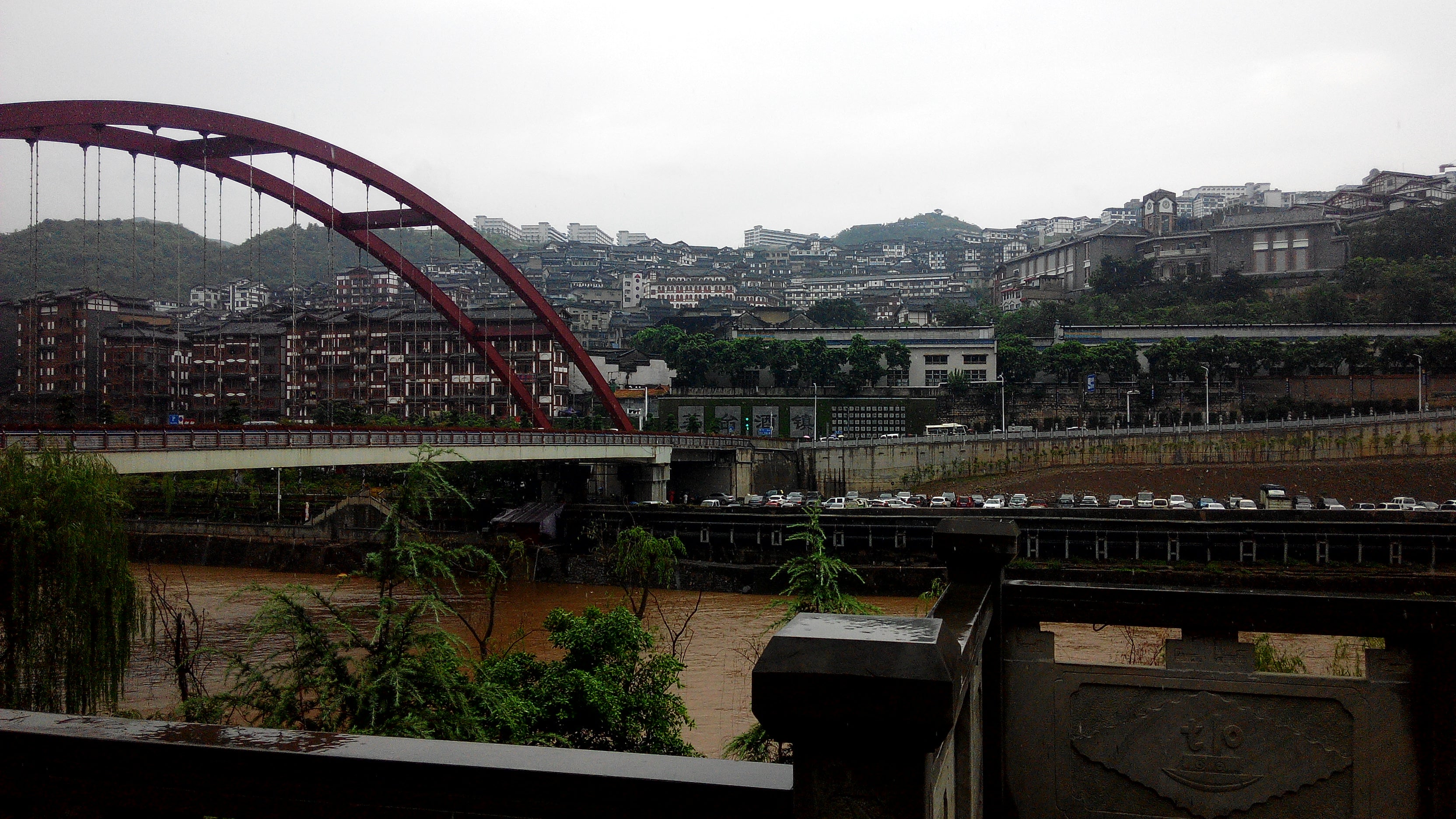 Red bridge and hillside buildings along the Chishui River in Maotai town, Guizhou.