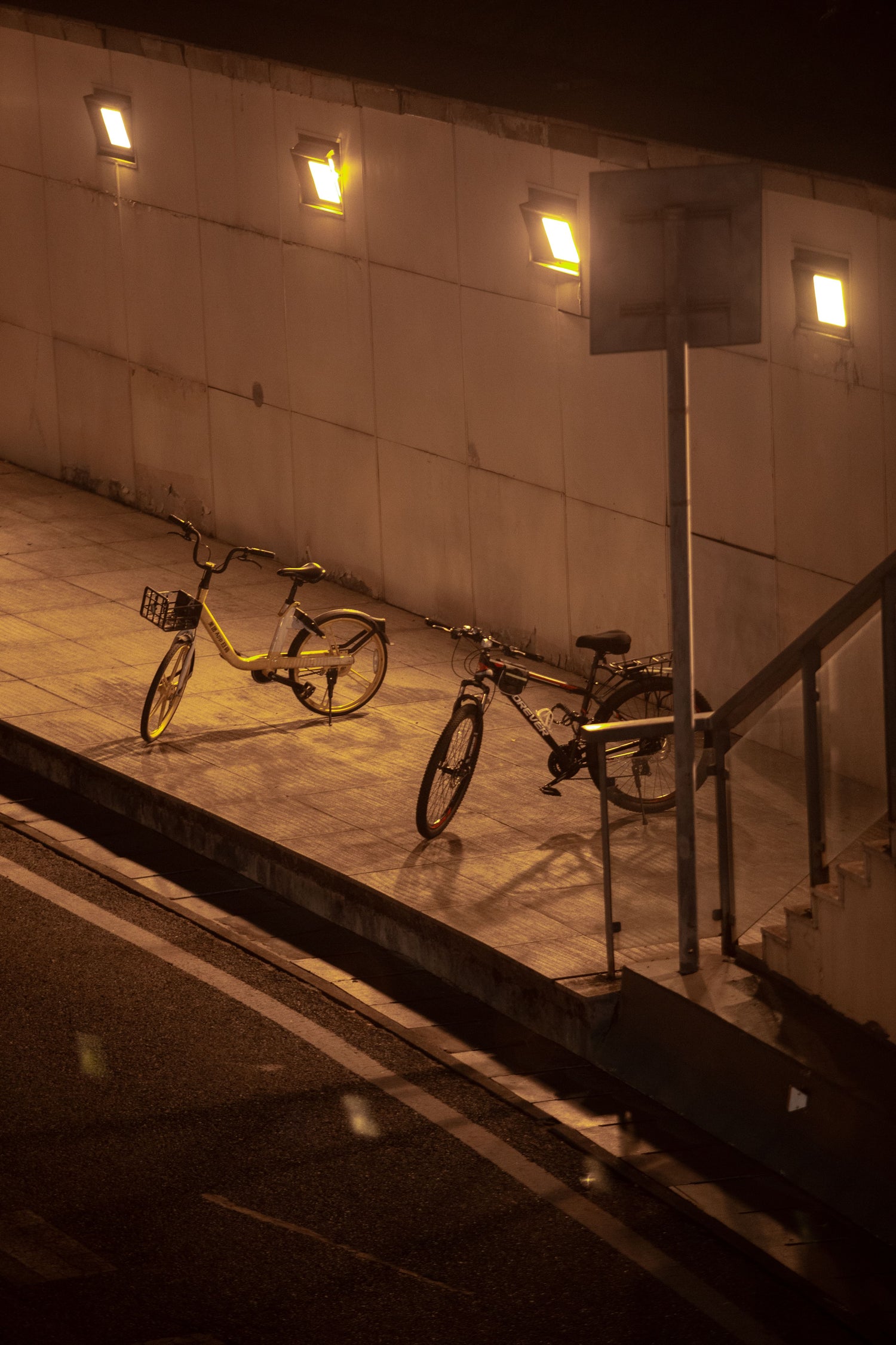 Two bicycles parked on a street in Hangzhou at night.
