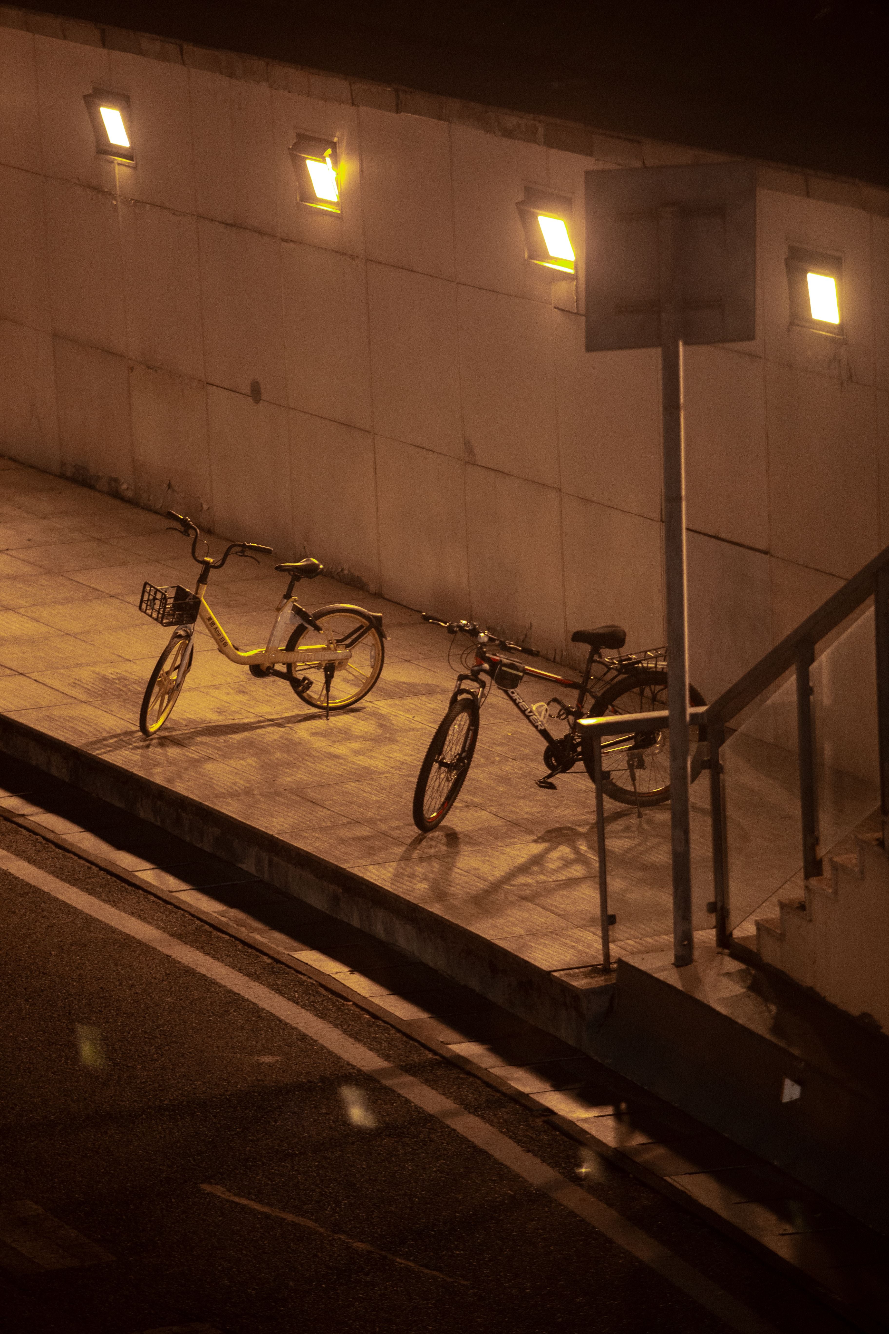 Two bicycles parked on a street in Hangzhou at night.