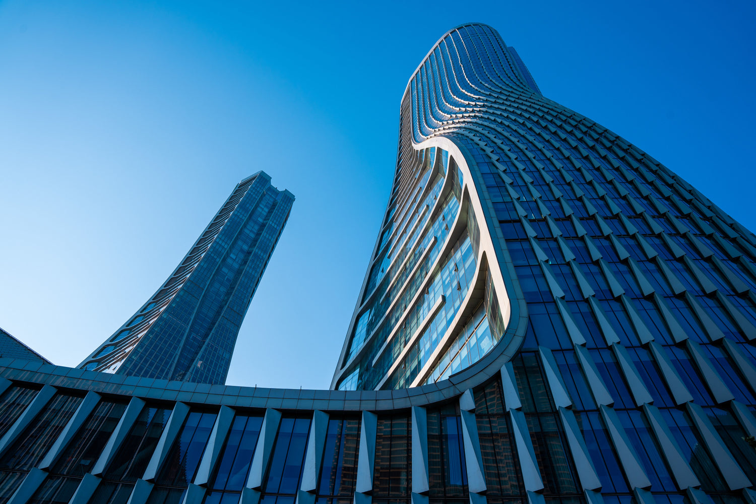 Modern glass buildings in Hangzhou under a clear blue sky.