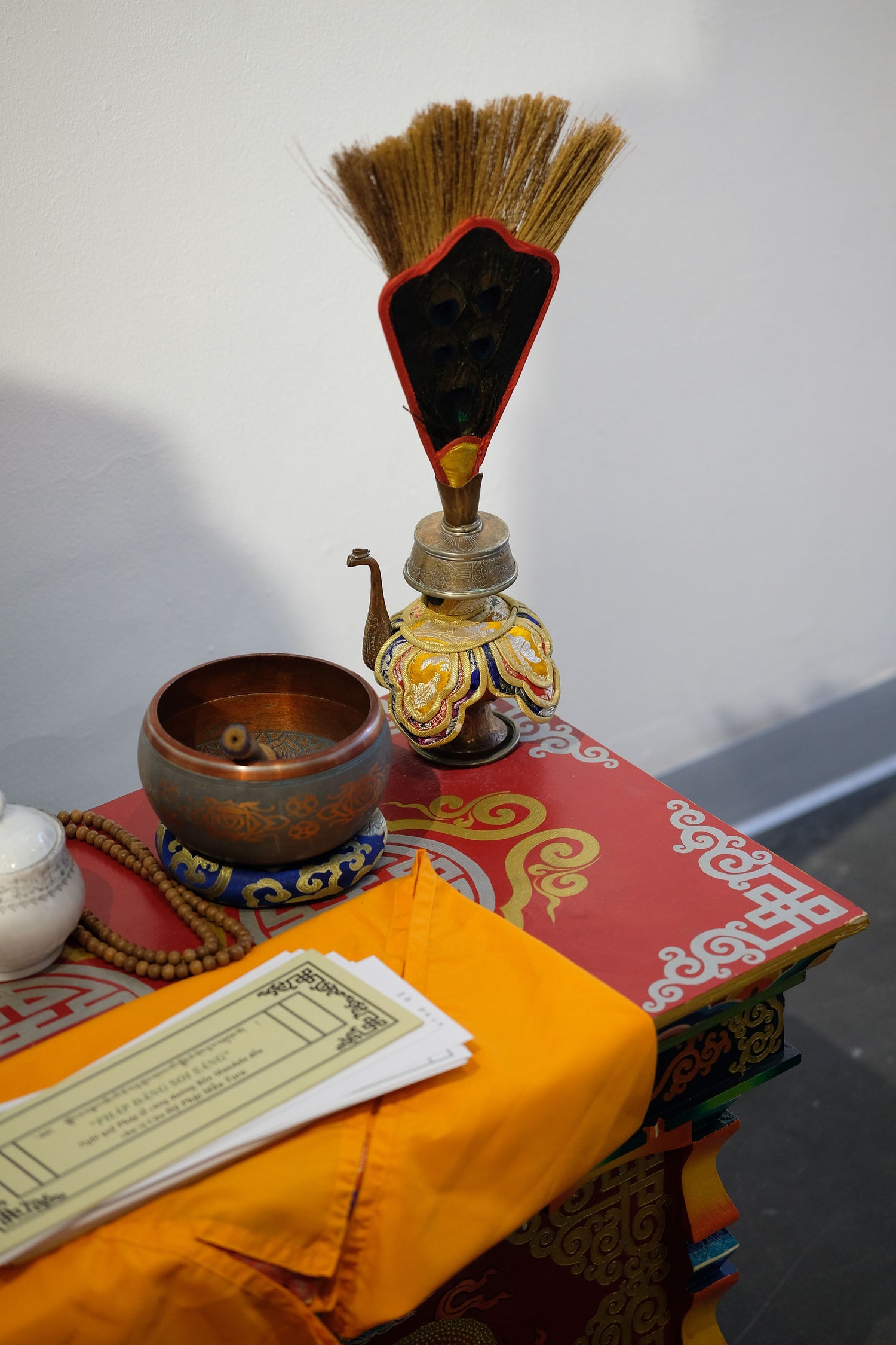 Bronze bowl, prayer beads and a decorated ceremonial vessel on a Tibetan ritual table.