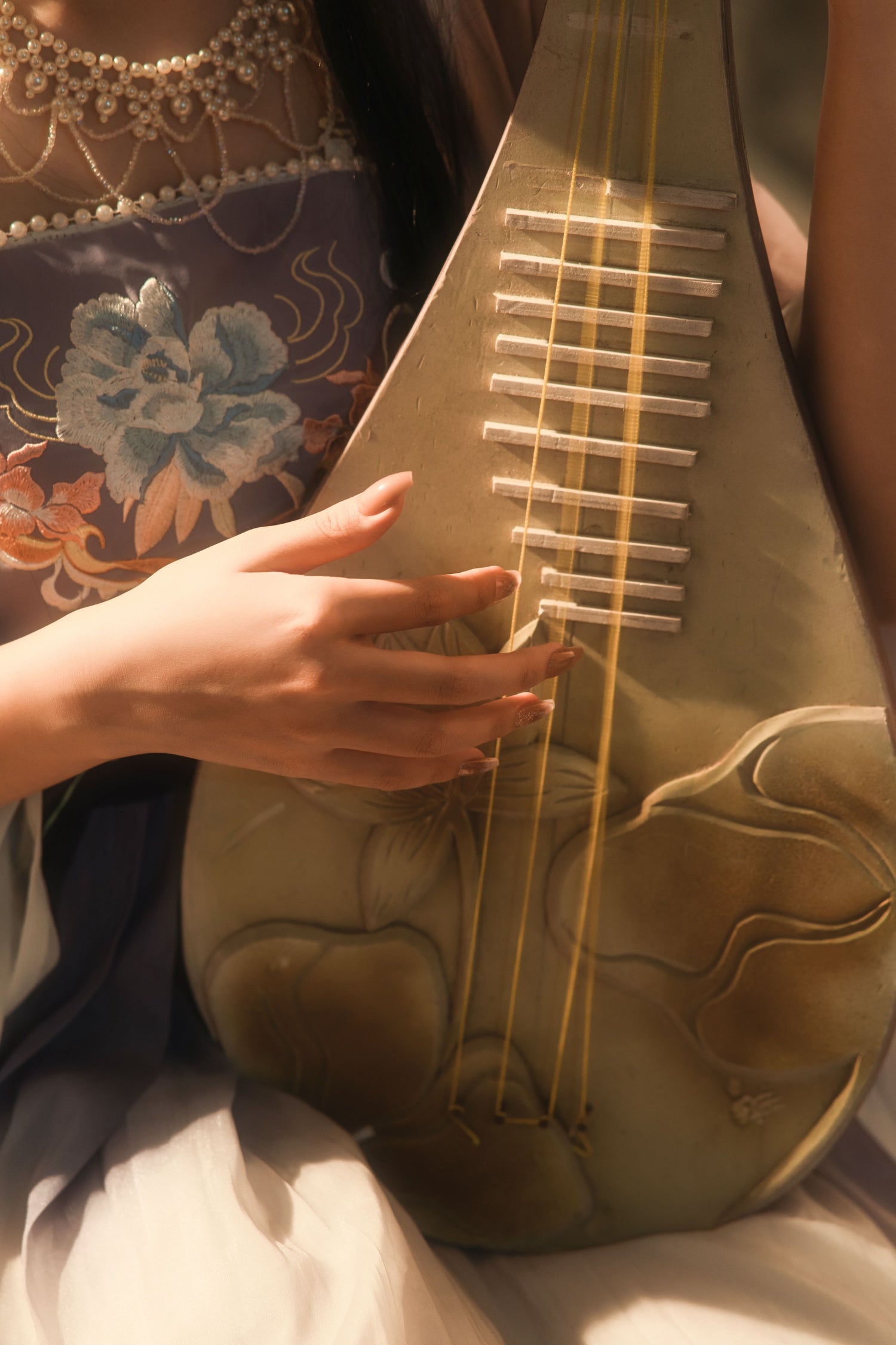 Hands plucking the strings of a traditional Chinese pipa.