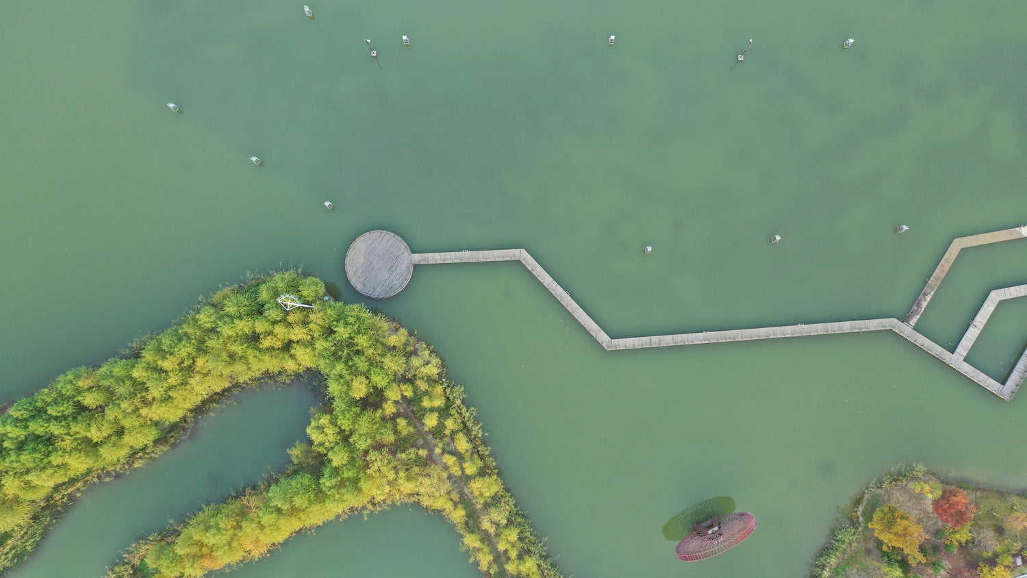 Aerial view of water, tree-covered wetland islands and a zigzag boardwalk at Taihu Wetland Park in Suzhou.