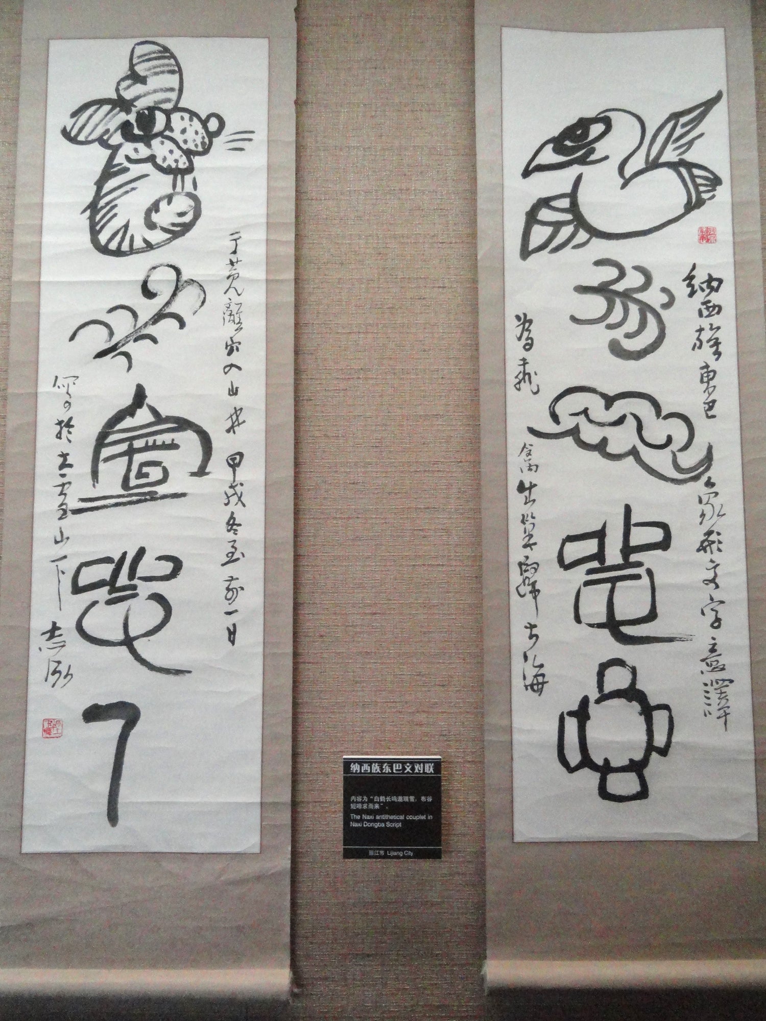 Naxi Dongba pictographic scrolls depicting birds and weather signs in a Yunnan museum.